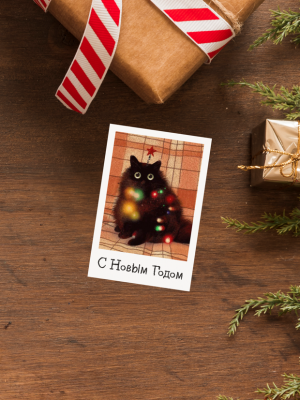 ОТКРЫТКА С ИЛЛЮСТРАЦИЕЙ ЧЁРНОГО КОТА С КРАСНОЙ ЗВЕЗДОЙ НА ГОЛОВЕ, В СВЕТЯЩЕЙСЯ РАЗНОЦВЕТНОЙ ГИРЛЯНДЕ, С ТЕКСТОМ “С НОВЫМ ГОДОМ” (6 х 9 см)