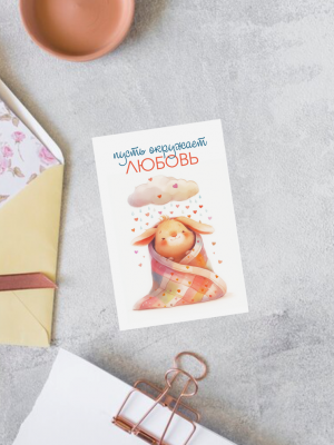 МИНИ-ОТКРЫТКА С ИЛЛЮСТРАЦИЕЙ ЗАЙКИ В ОДЕЯЛЕ, И ТЕКСТОМ "ПУСТЬ ОКРУЖАЕТ ЛЮБОВЬ" (6х9 см)